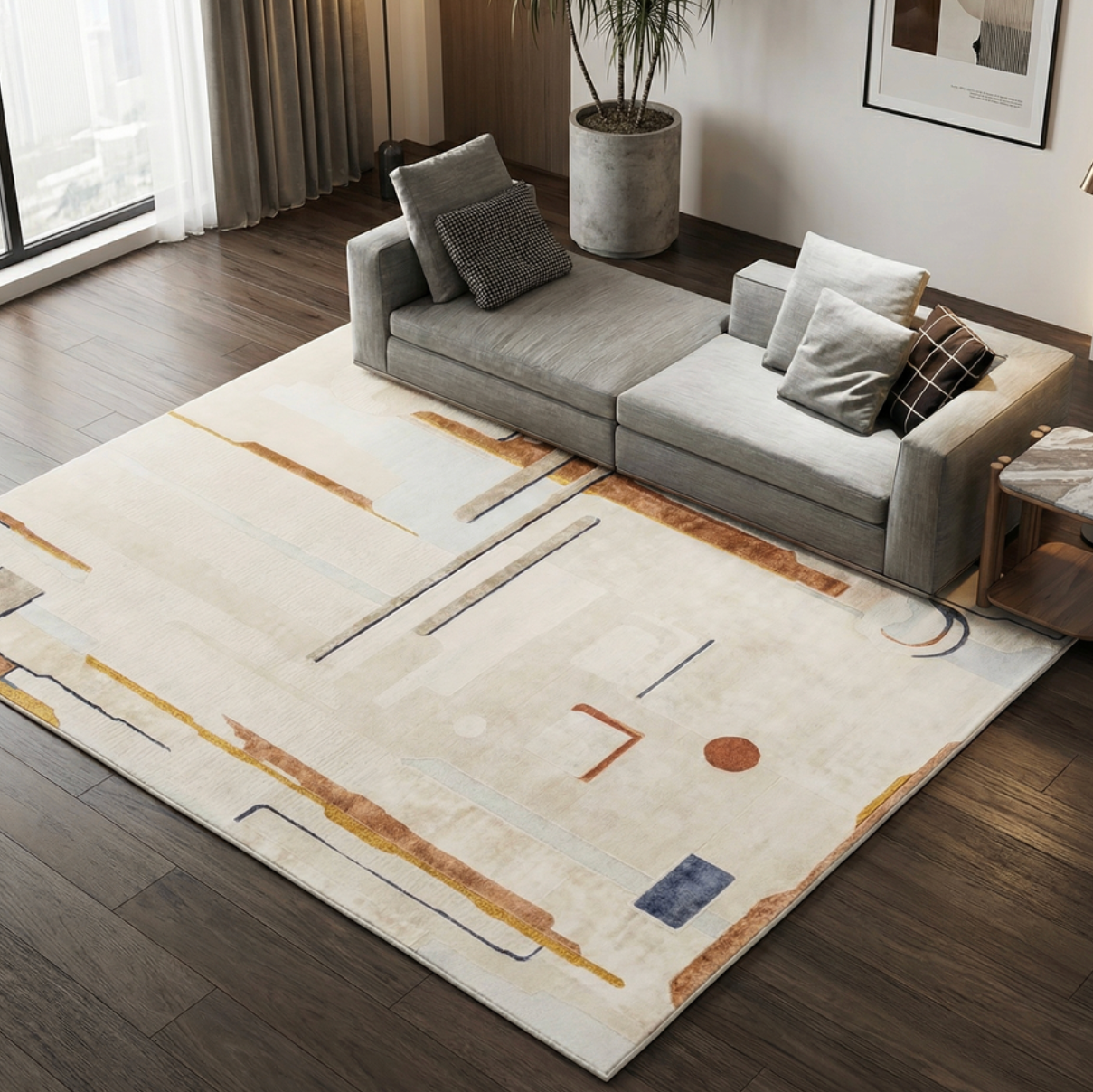 A large modern area rug with an abstract geometric pattern in beige, white, brown, and muted blue, styled in a contemporary living room next to a gray sofa.