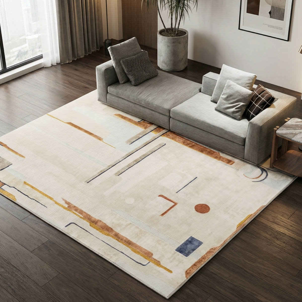 A large modern area rug with an abstract geometric pattern in beige, white, brown, and muted blue, styled in a contemporary living room next to a gray sofa.